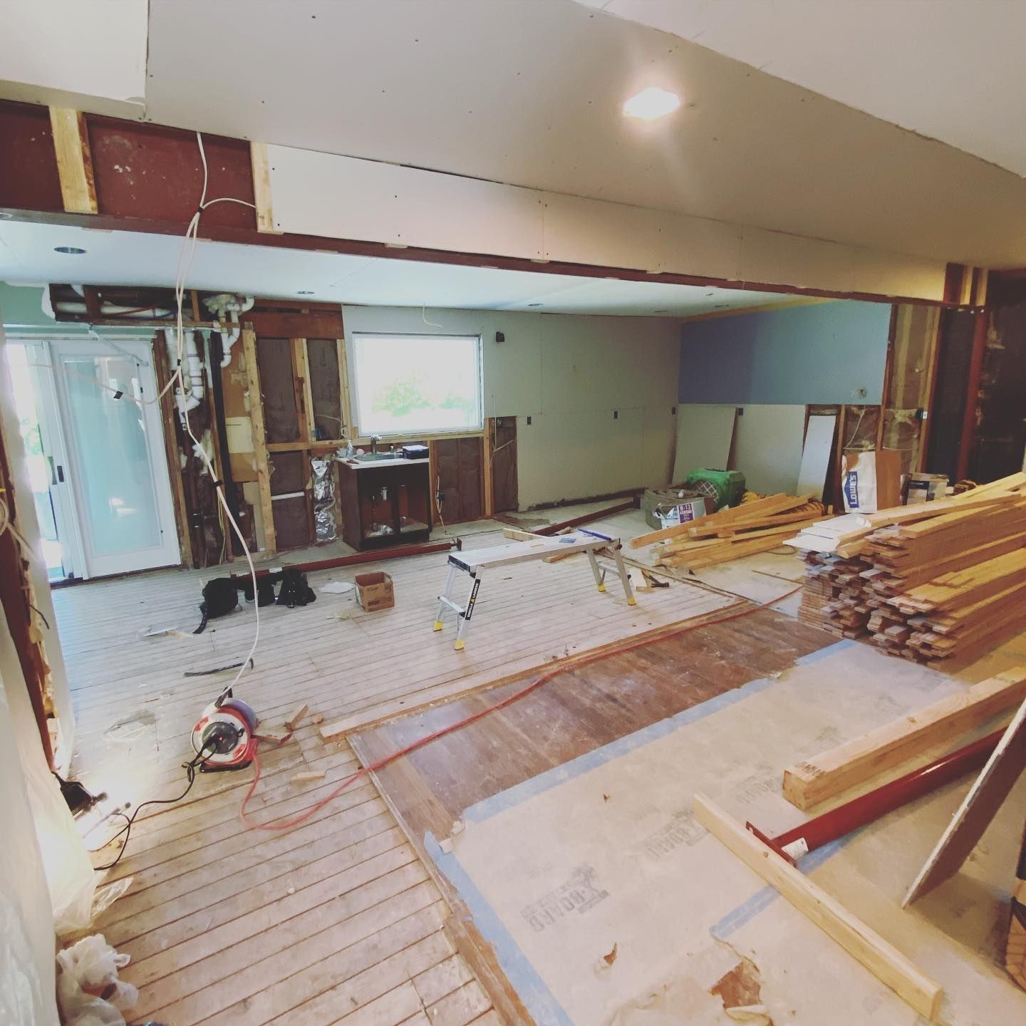 Interior renovation: walls stripped, flooring exposed, construction debris.