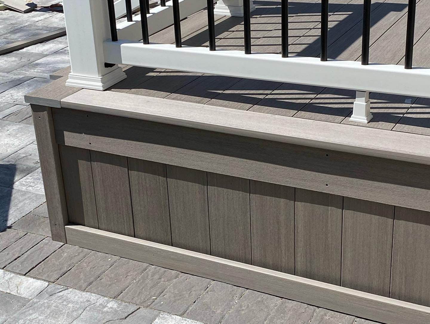 Composite deck with a skirt board featuring vertical planks, topped with a railing and balusters.