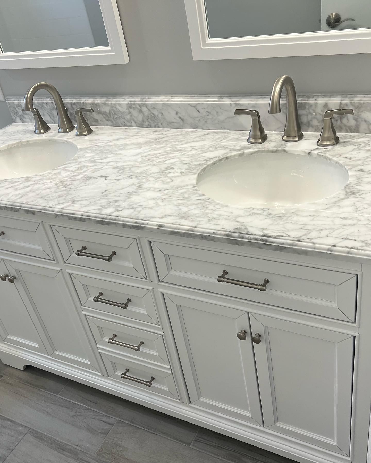 White bathroom vanity with marble countertop, two sinks, and brushed nickel fixtures.