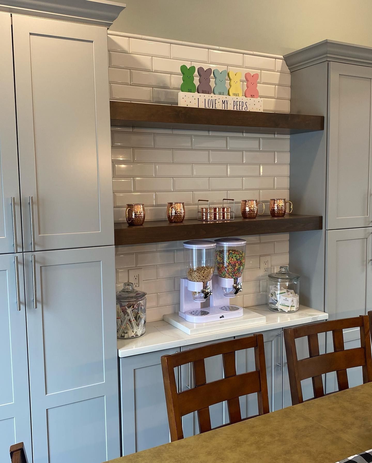 Gray kitchen cabinets with shelves, white subway tile backsplash, and Easter decorations.