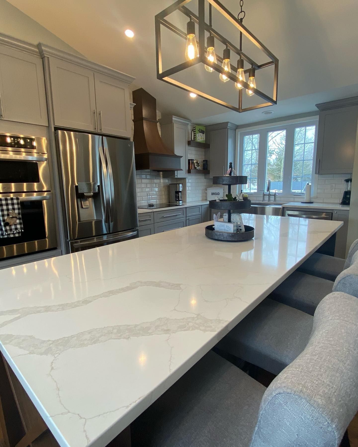 Modern kitchen with a white countertop island and grey cabinets.