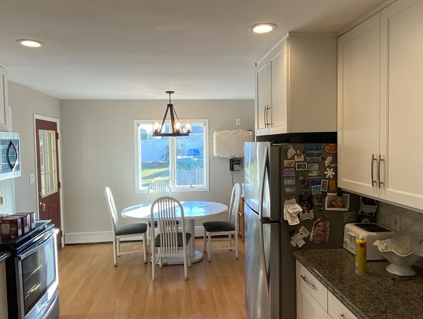 Kitchen with white cabinets, round table, chairs, and wood floors.
