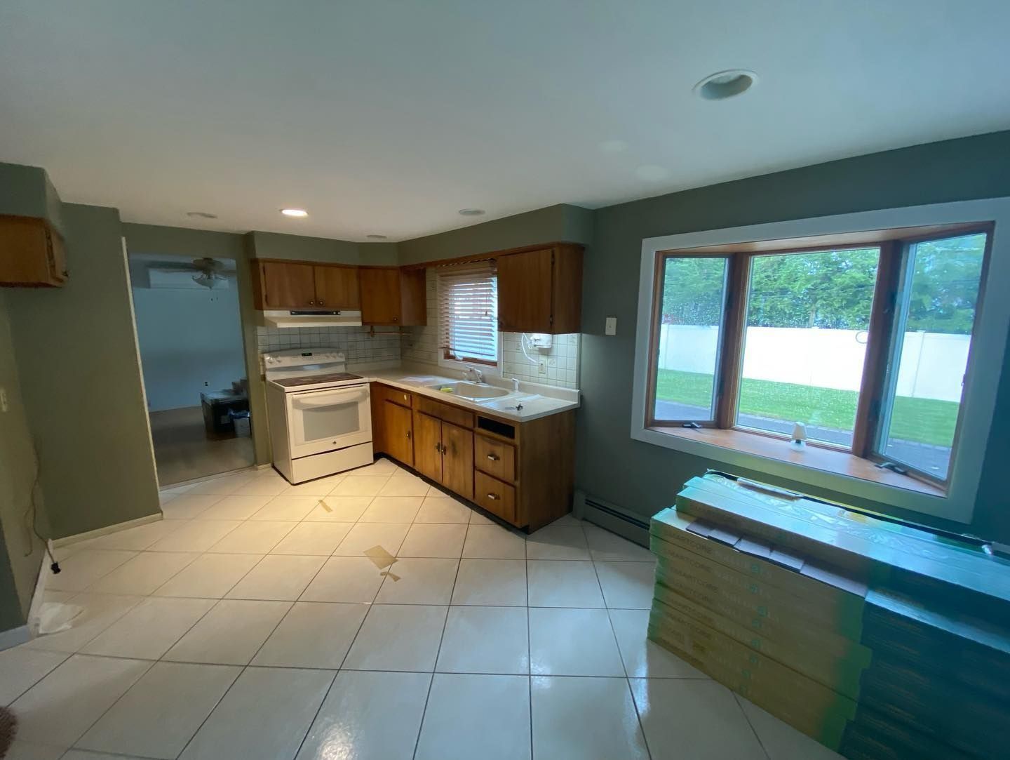 Kitchen with light tile floors, wooden cabinets, white stove, and bay window.
