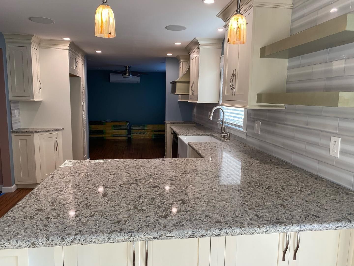 Granite countertop in a kitchen with cream cabinets, mosaic backsplash, and pendant lights.