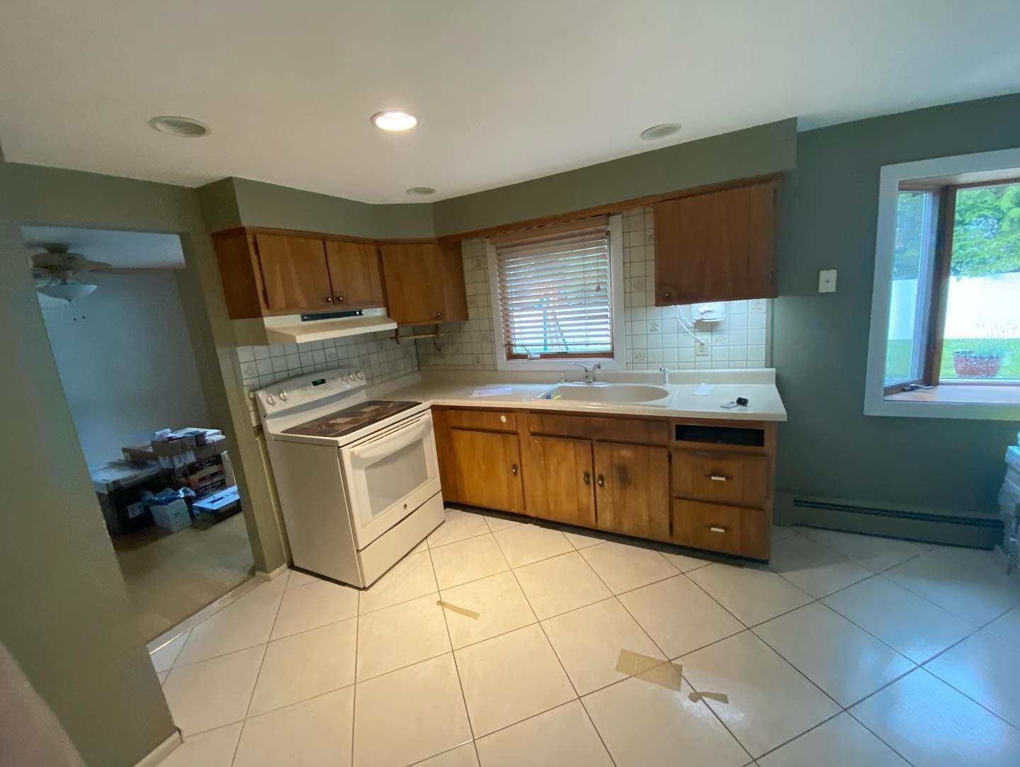 Kitchen with wood cabinets, white stove, and tile floor. Green walls and a window are visible.