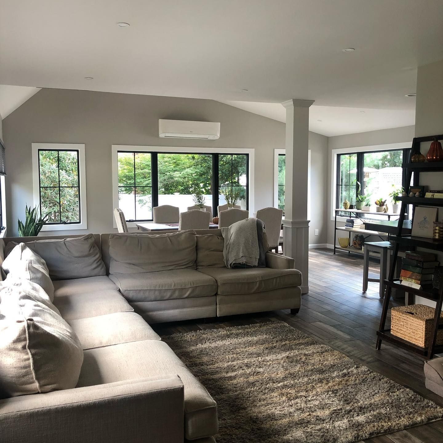 Spacious living room with sectional sofa, rug, and dining area visible through large windows.