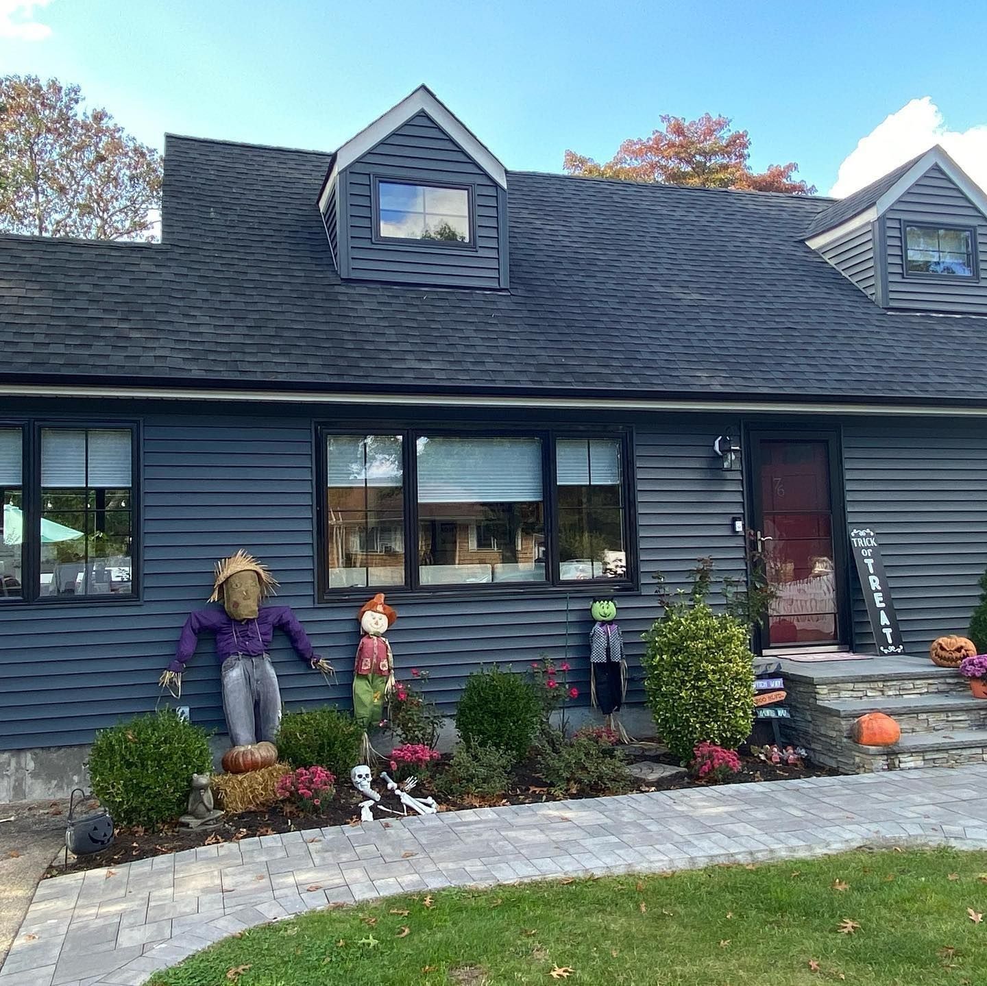 House with Halloween decorations: scarecrows, pumpkins, and a 