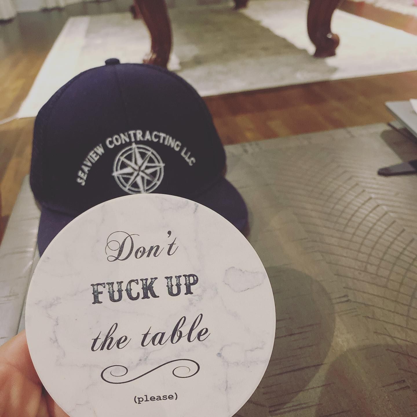 A navy hat with logo next to a coaster that says 