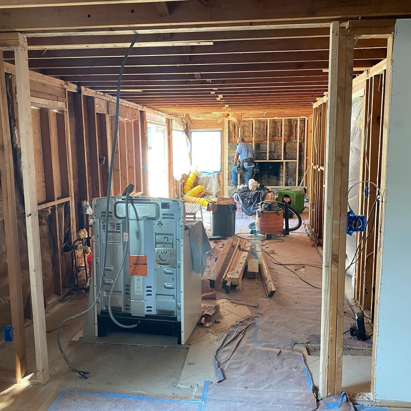 Interior of a home under construction, with exposed wood framing, appliances, and tools.