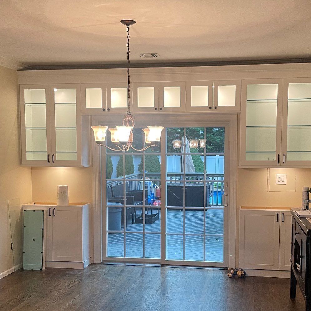 Kitchen with white cabinets, chandelier, and glass sliding door overlooking a patio.