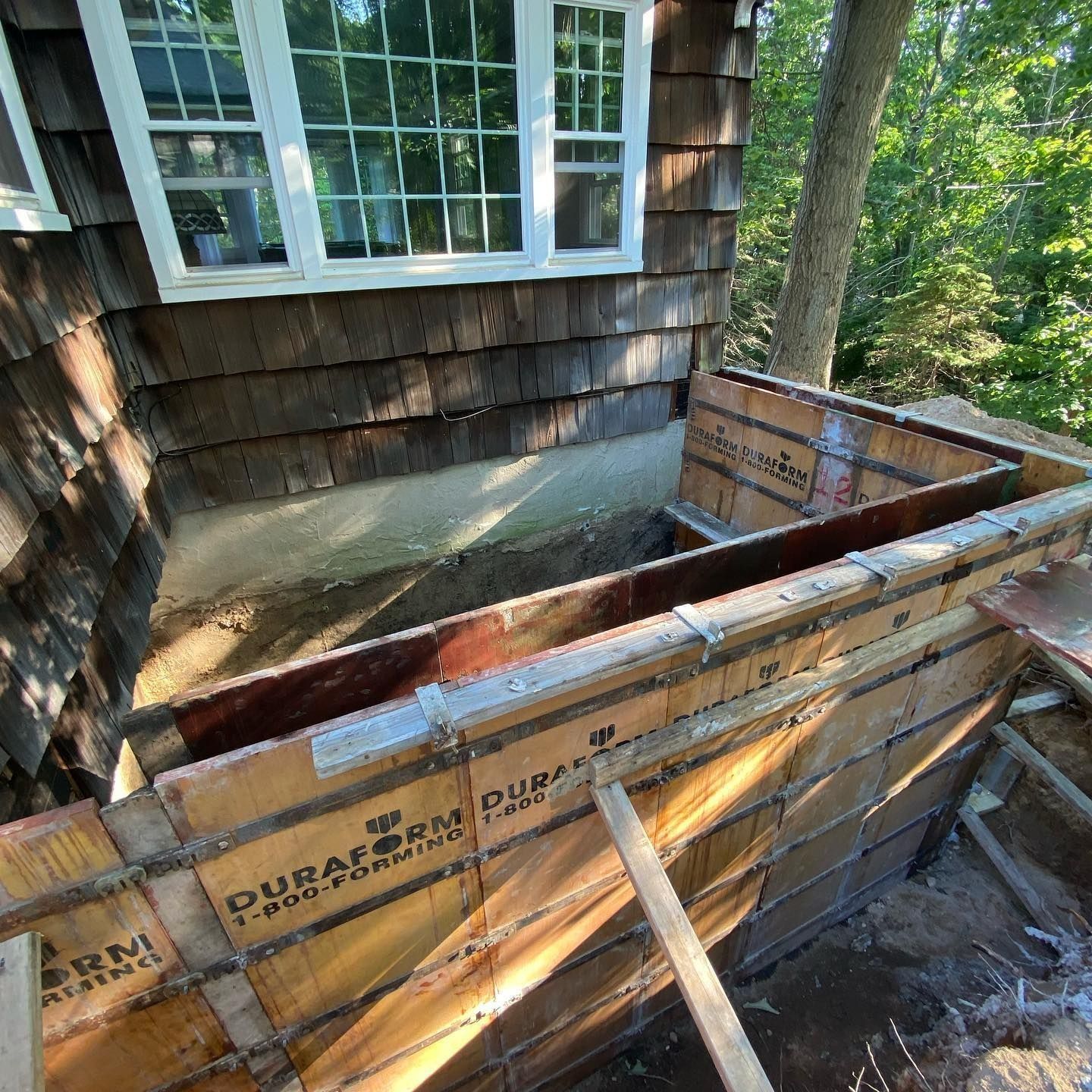 Exterior wall construction: Wood siding, window above, concrete foundation, formwork.