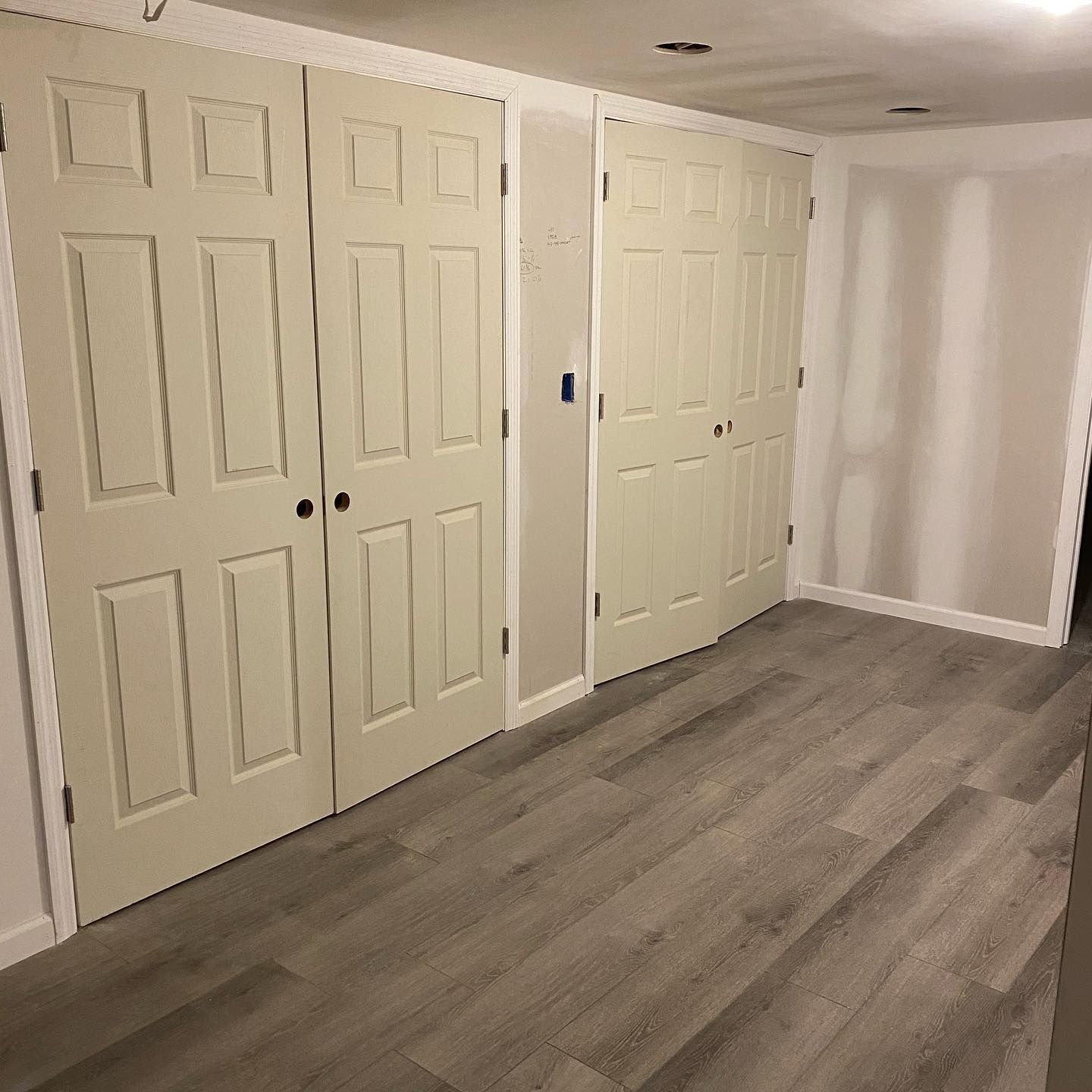 Closet doors in a room with gray flooring and white walls.