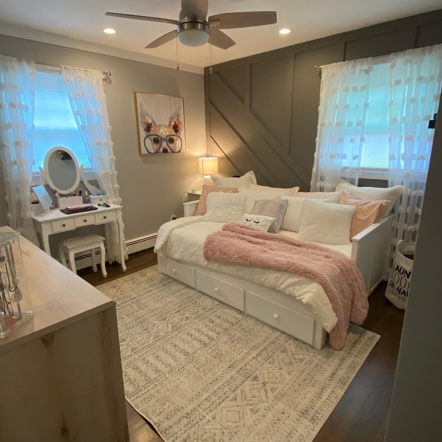 Bedroom with a white daybed, vanity, and light gray and pink decor.