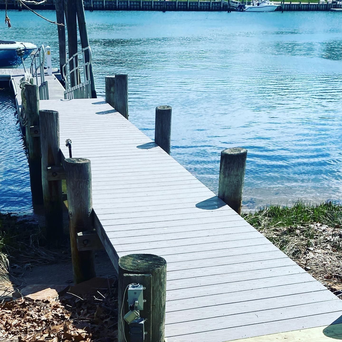 Wooden dock with ramp, posts, and blue water in background.