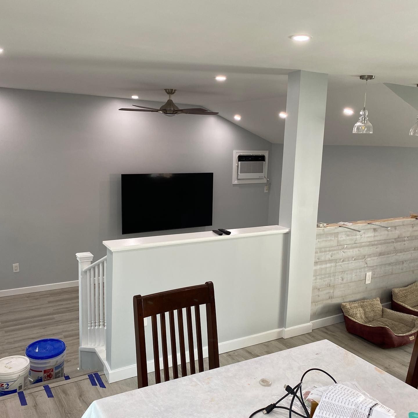 Interior view of a living space with gray walls, a TV, and a dining area with a table and chair.