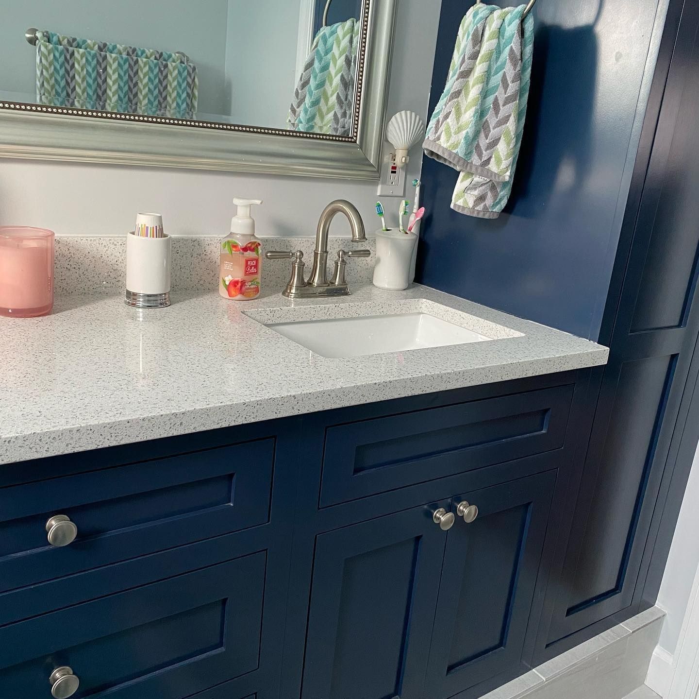 Blue bathroom vanity with white countertop, sink, mirror, and towels.