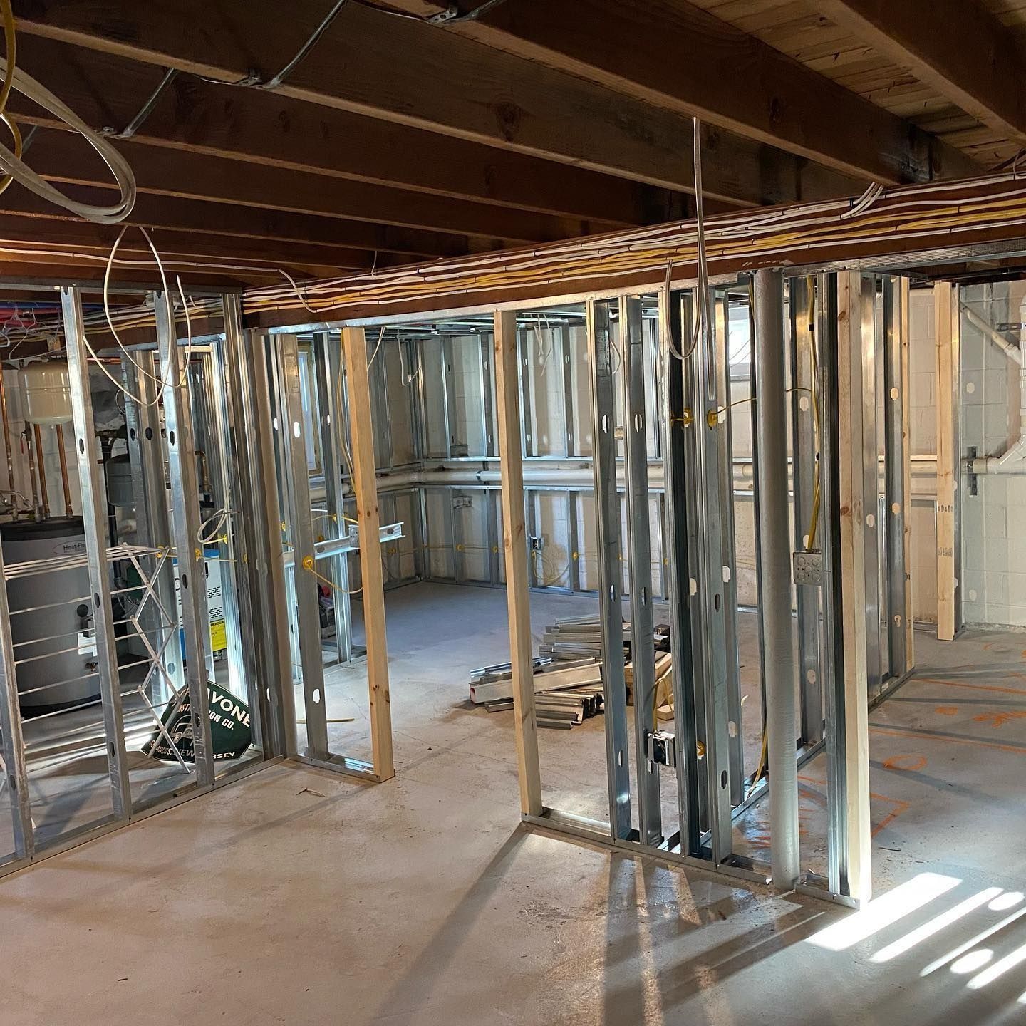 Interior view of a basement renovation with metal studs and exposed ceiling joists.