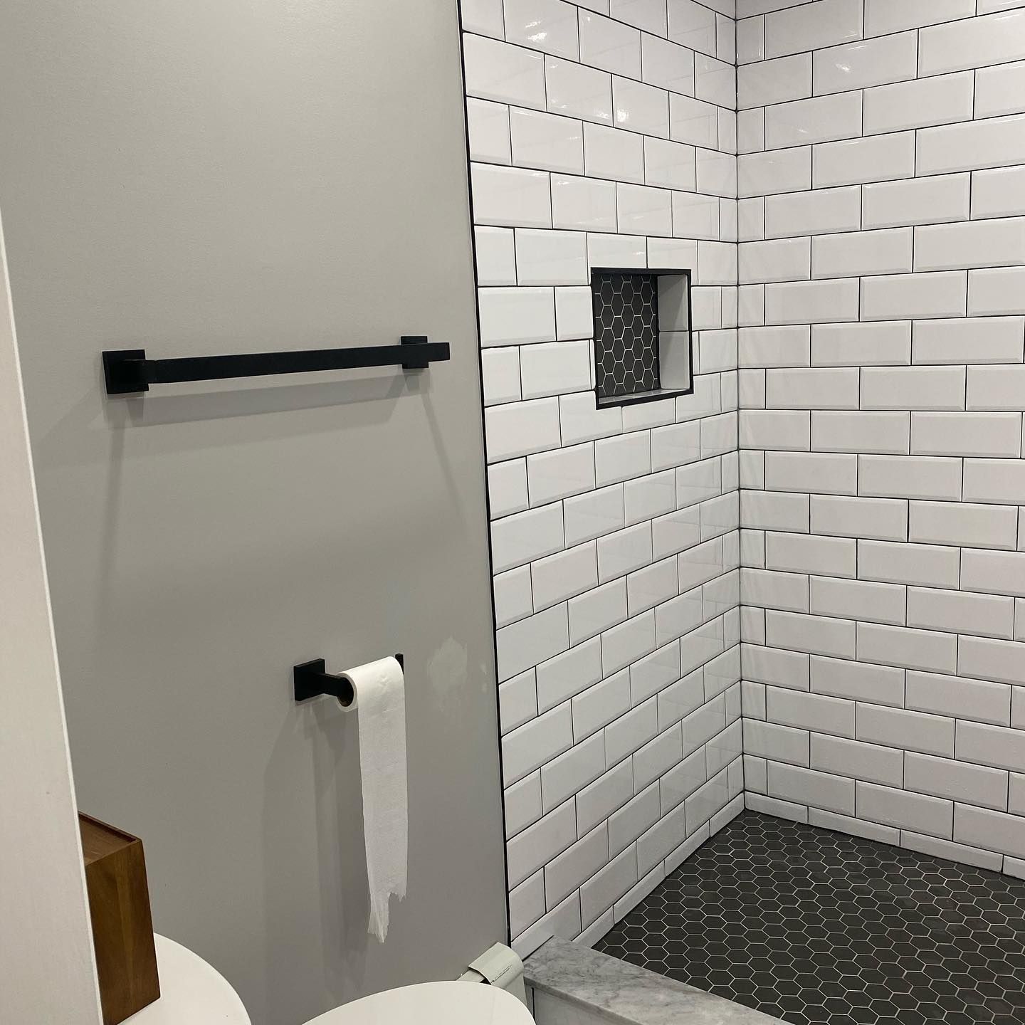 Bathroom interior with white subway tiles, dark accents, and a stone shower floor.
