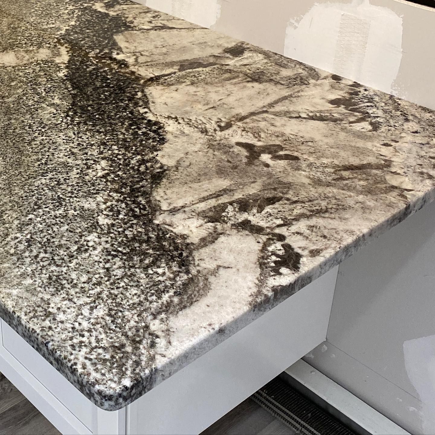Granite countertop with black, white, and gray patterns, installed on white cabinets.