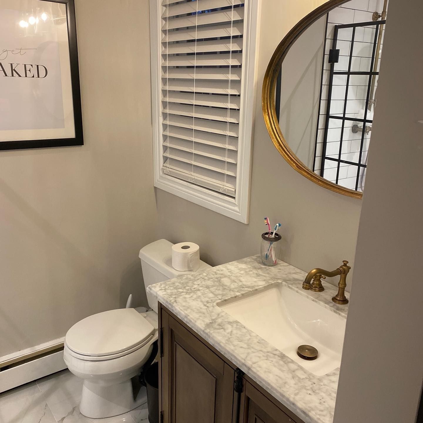 Bathroom with toilet, vanity with sink, mirror, and a framed art piece.