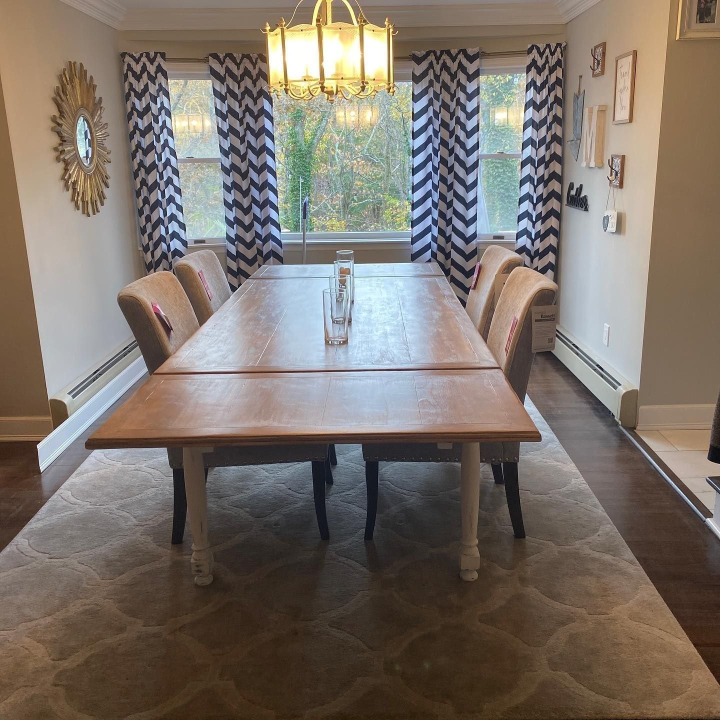 Dining room with a wooden table, chairs, patterned curtains, and a chandelier.