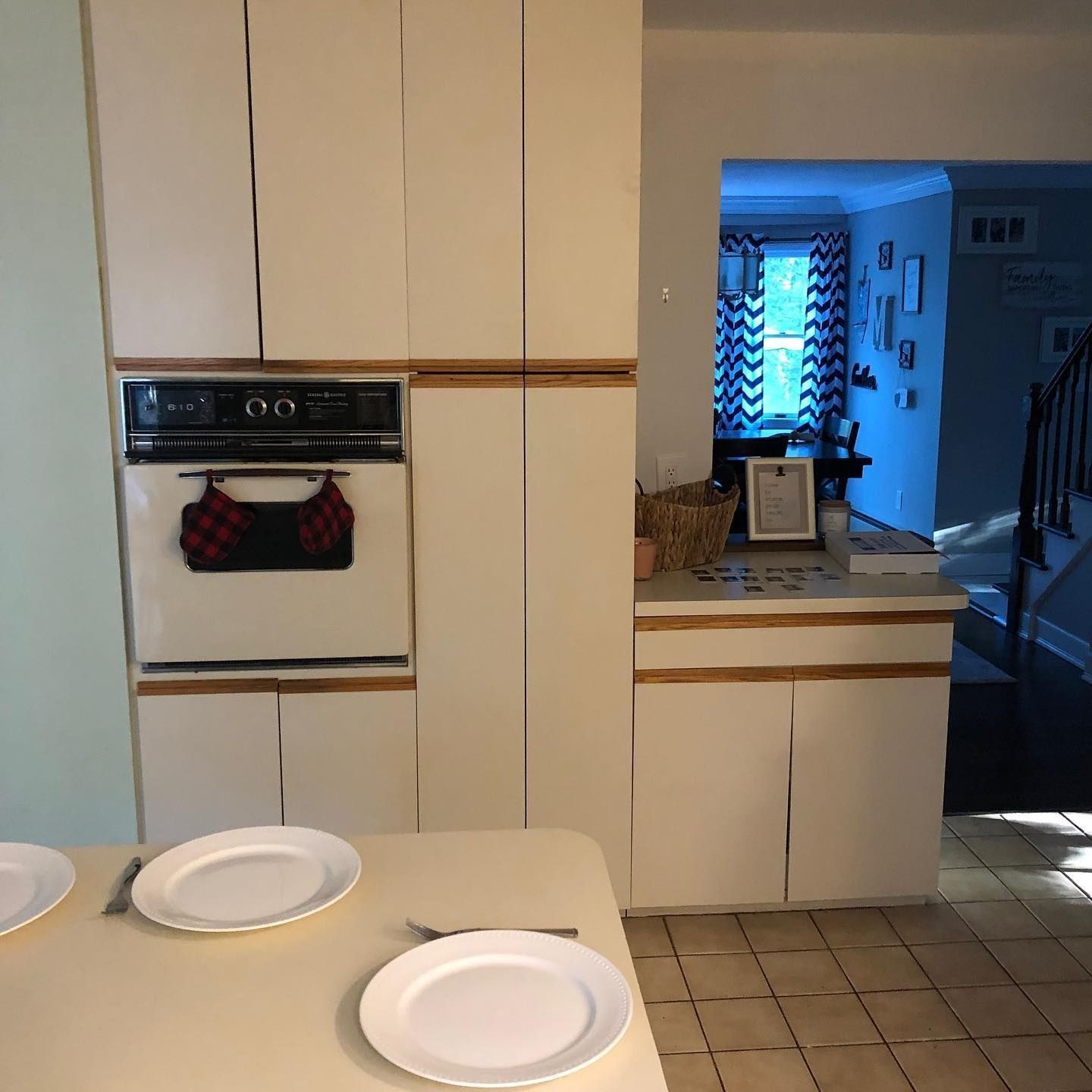 Kitchen with white cabinets, built-in oven, and a dining table set with plates.