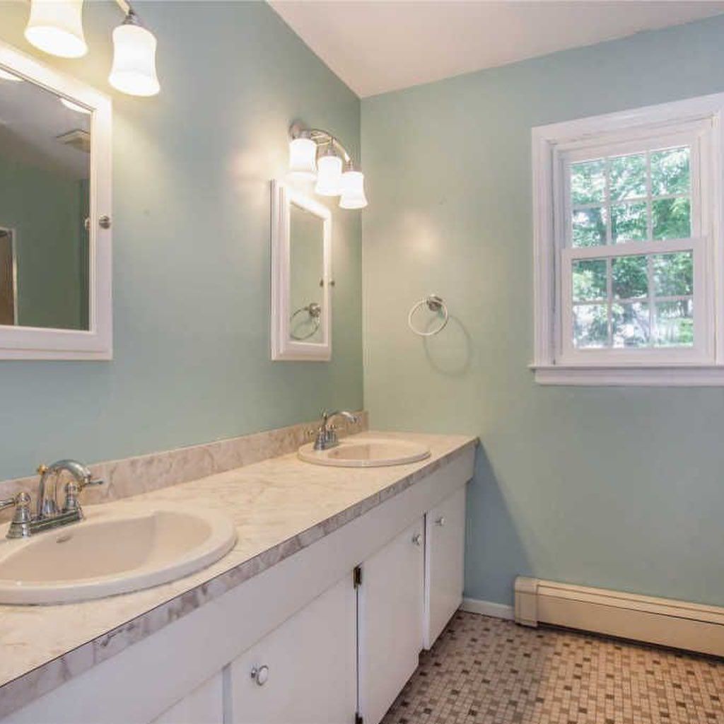 Bathroom with two sinks, a window, and light blue walls.