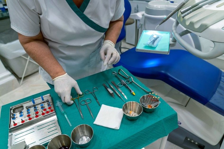 Dentista con strumenti odontoiatrici su un tavolo