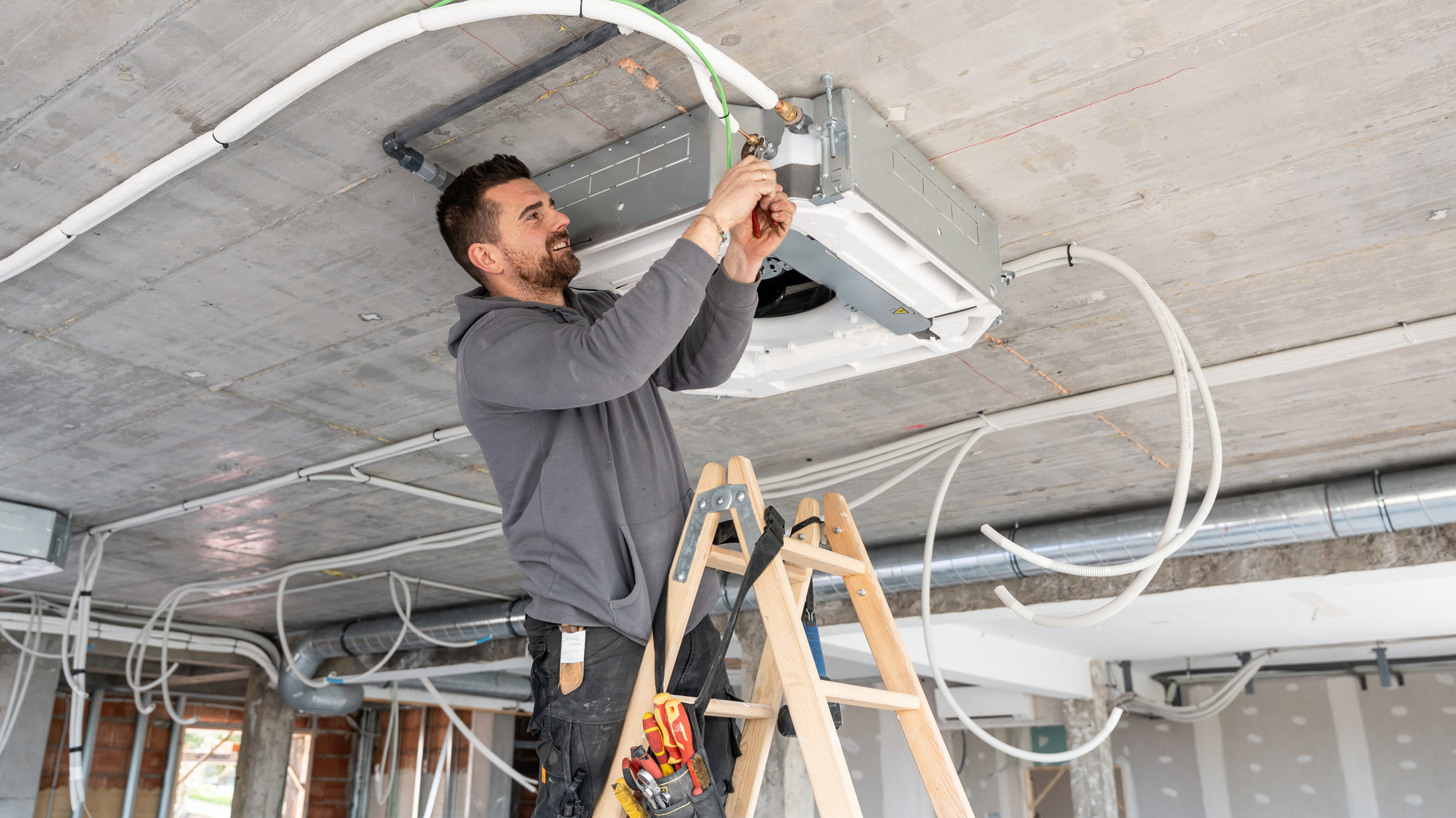 Air conditioning units with toolbox and gloves in backyard.