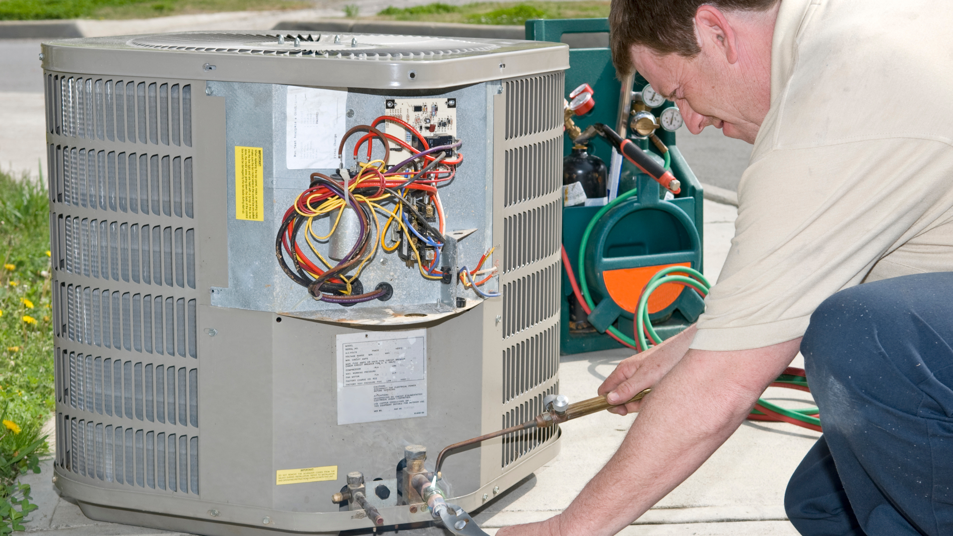 Air conditioning units with toolbox and gloves in backyard.