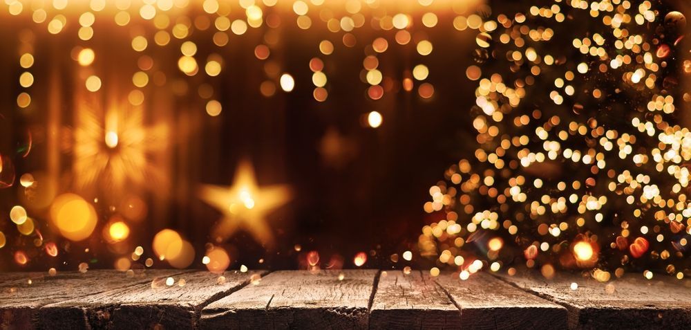 Warm holiday lights and a glowing Christmas tree beside a rustic wooden floor