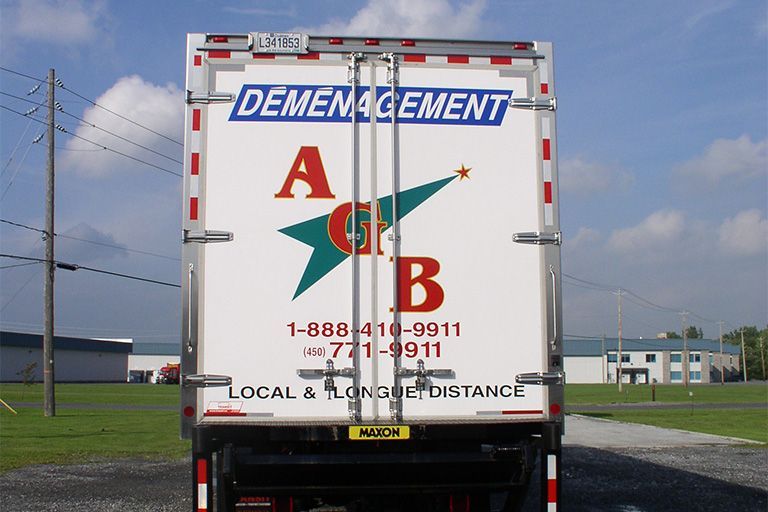 Vue arrière d'un camion de déménagement ; blanc avec des accents rouges et bleus.