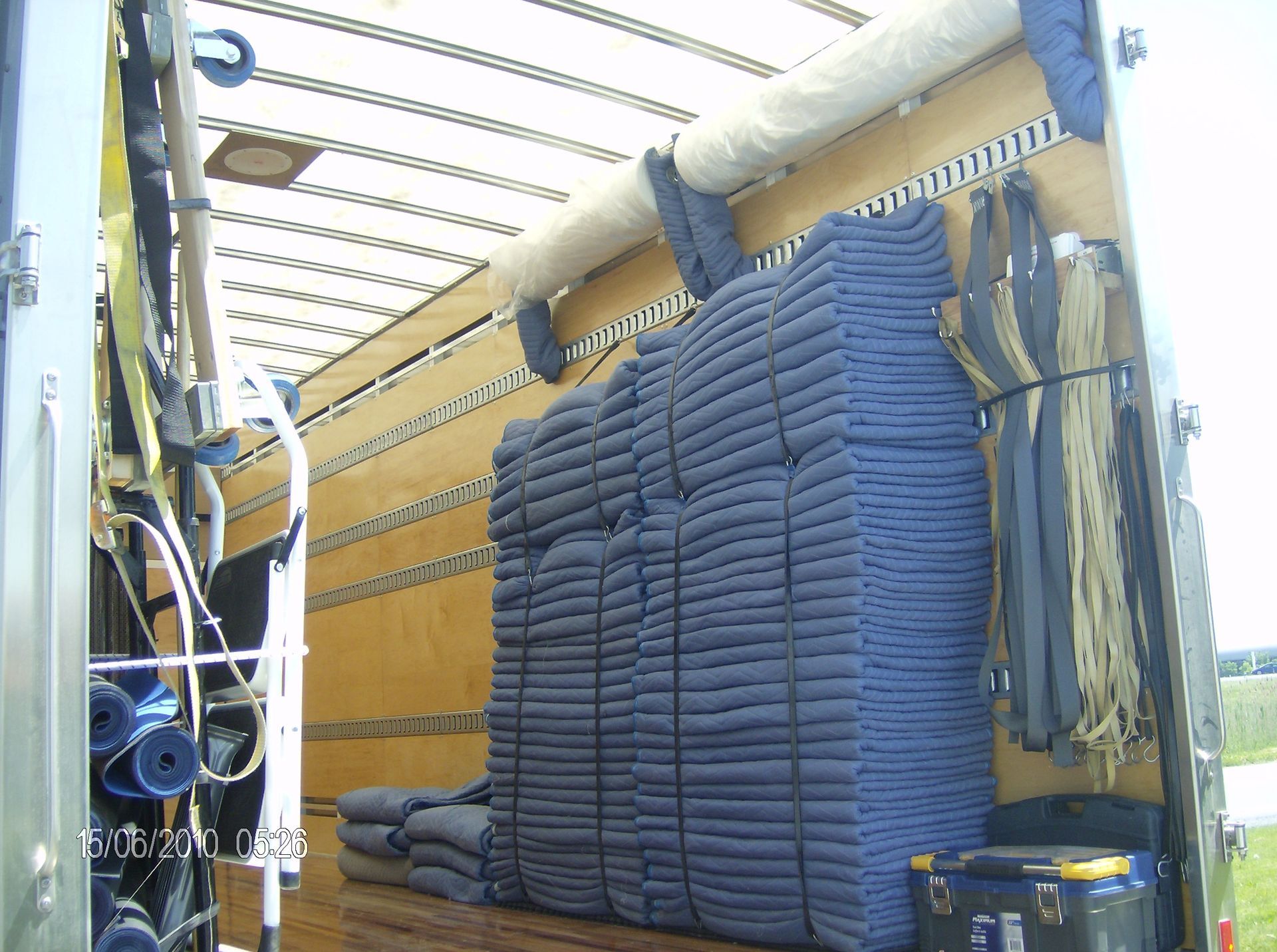 À l'intérieur d'une remorque de camion, une grande pile de couvertures bleues pliées.