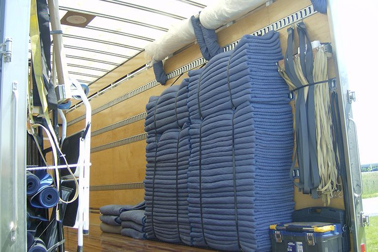 À l'intérieur d'un camion : couvertures bleues, cordes et équipement empilés.