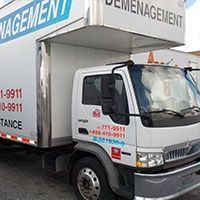 Camion de déménagement, cabine blanche avec logos rouges et bleus, stationné. Inscription « Déménagement » sur le côté.