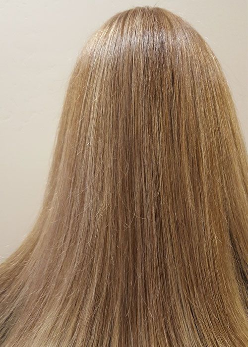 A close up of a woman 's long blonde hair against a white background.