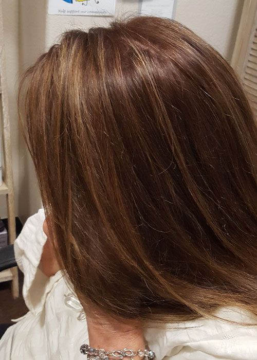 A woman with long brown hair is wearing a white shirt and a bracelet.