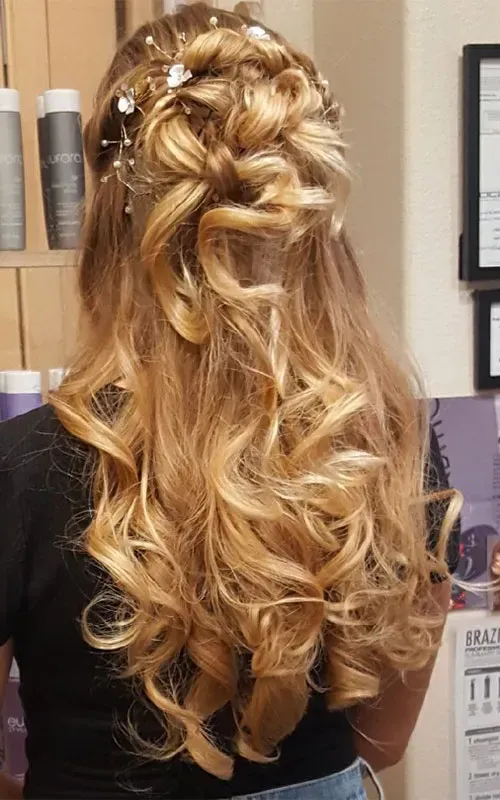 A woman with long blonde hair is wearing a half up half down hairstyle.