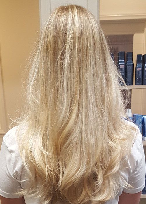 A woman with long blonde hair is wearing a white shirt.