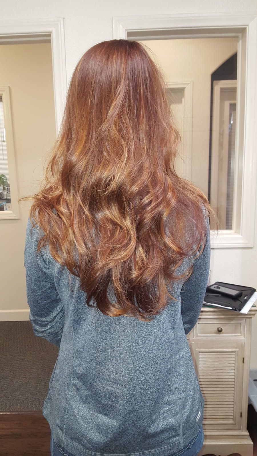 A woman with long brown hair is standing in front of a mirror.