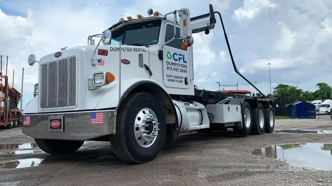 A white semi truck is parked in a gravel lot.