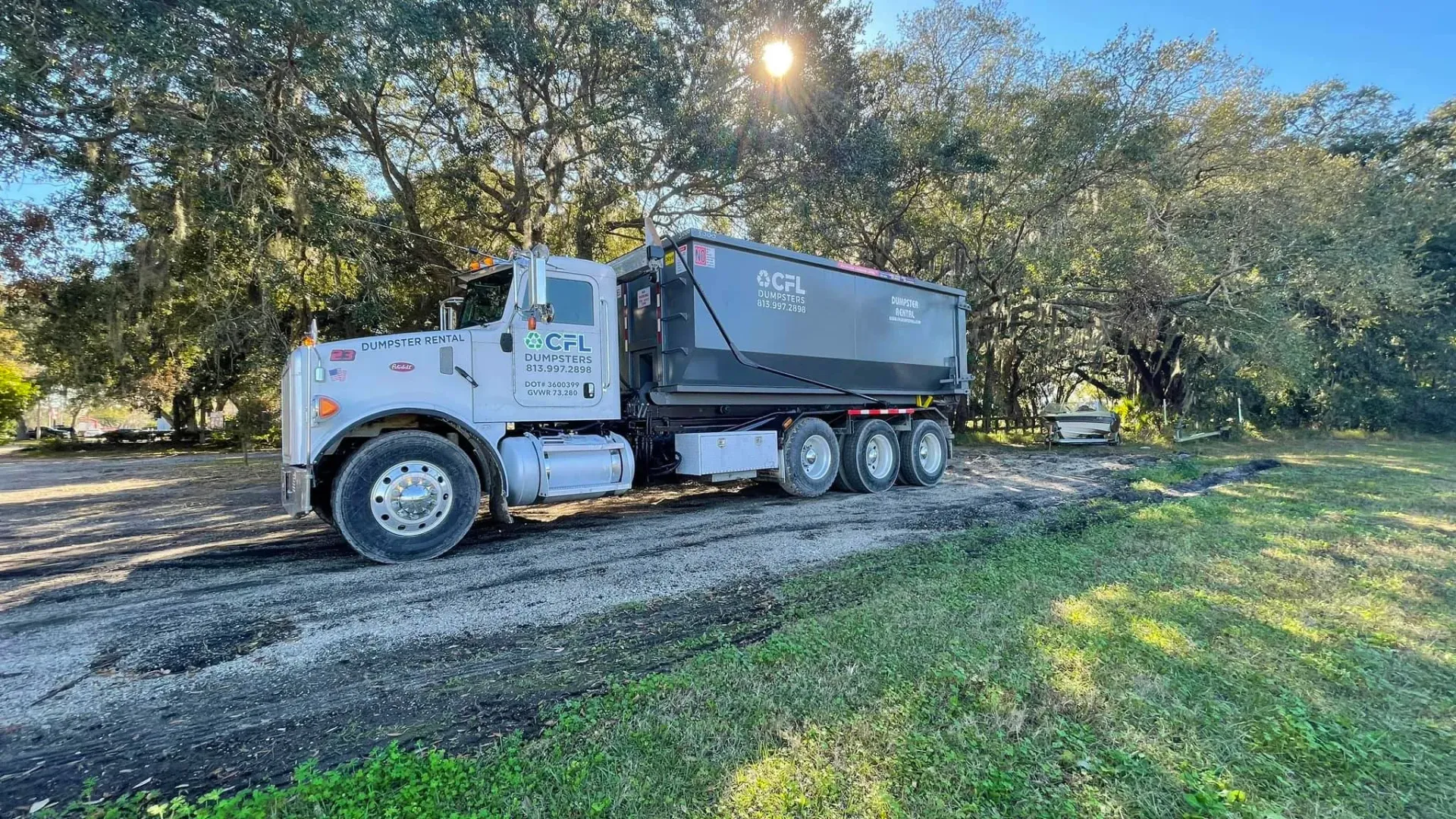 A dump truck is parked on the side of a dirt road.