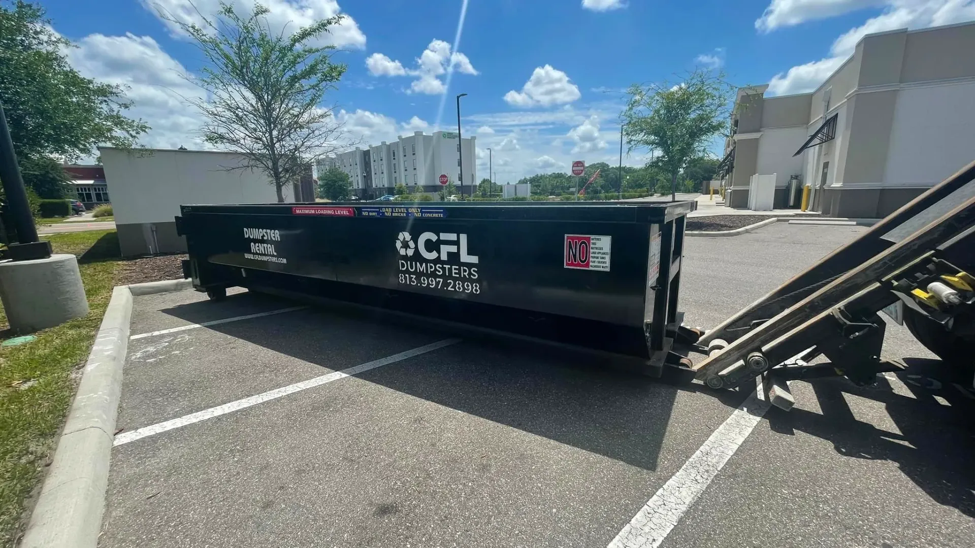 A dumpster is sitting in a parking lot next to a building.