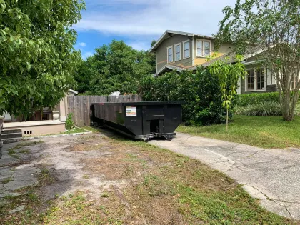 A dumpster is parked in the driveway of a house.