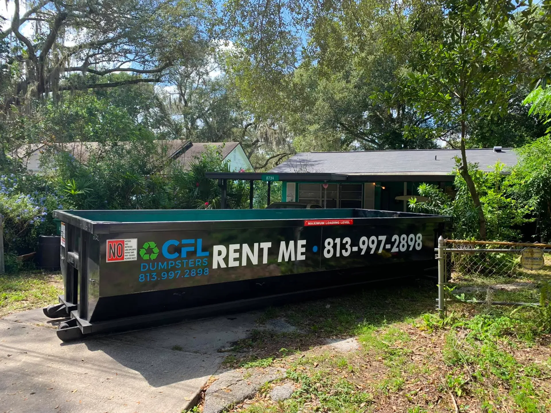 A dumpster is parked in front of a house.