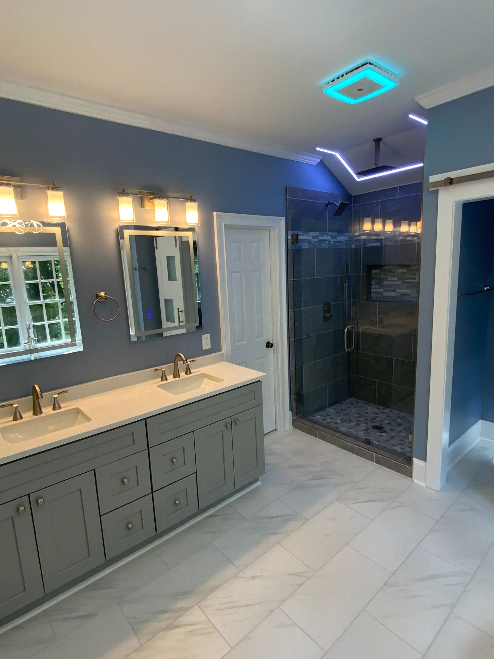 A bathroom with a walk in shower , sink , toilet and mirror.