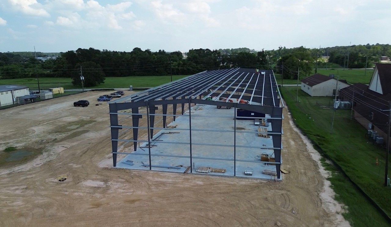 Interior view of a large metal building with steel beams and white walls.