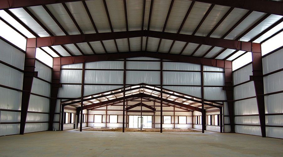 Interior view of a large metal building with steel beams and white walls.
