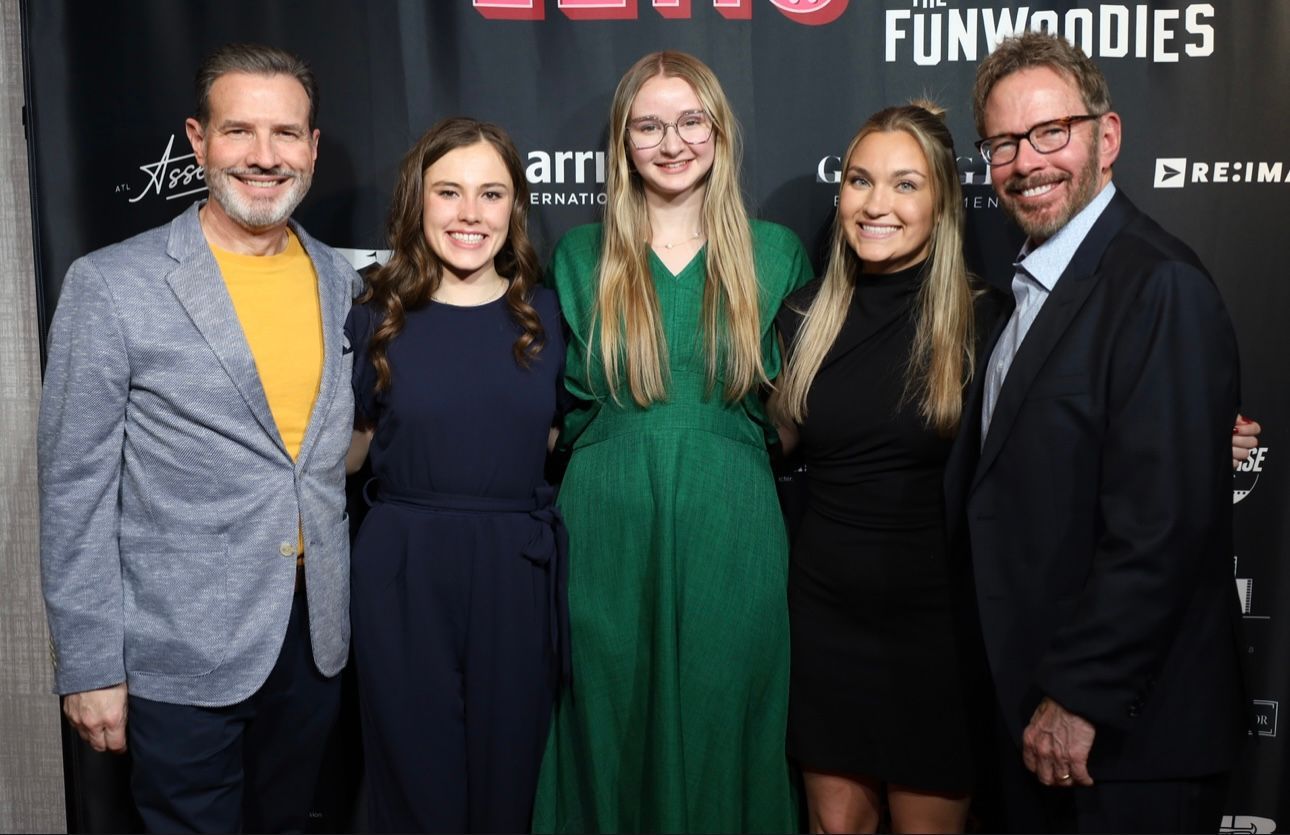 A group of people standing next to each other on a red carpet.