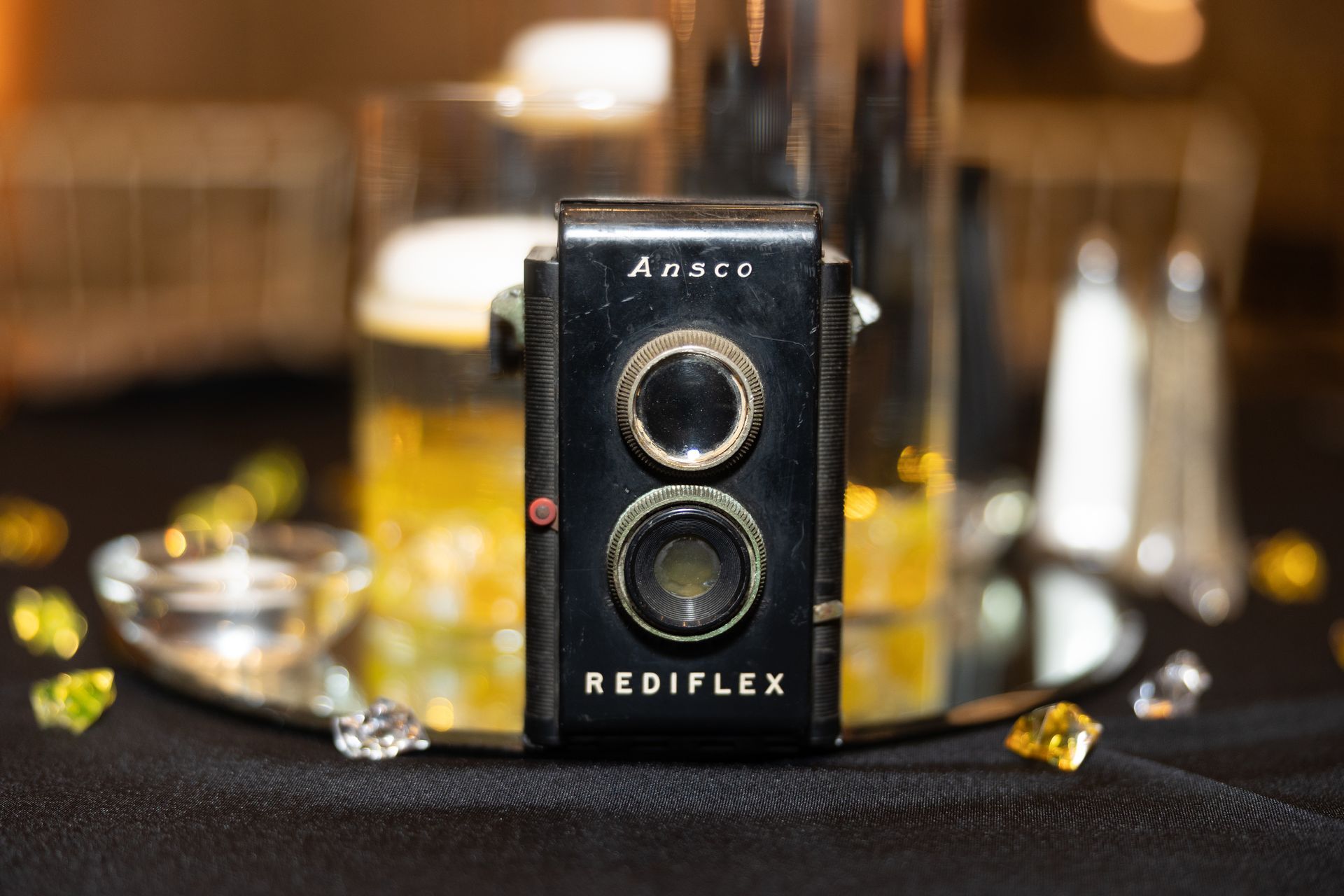 A rediflex camera is sitting on a table next to a glass of beer.